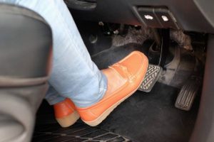 closeup foot pressing brake pedal of car